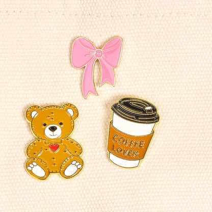 3pins including a pink bow, teddy bear, and coffee cup with 'Coffee Lover' text on a beige background.