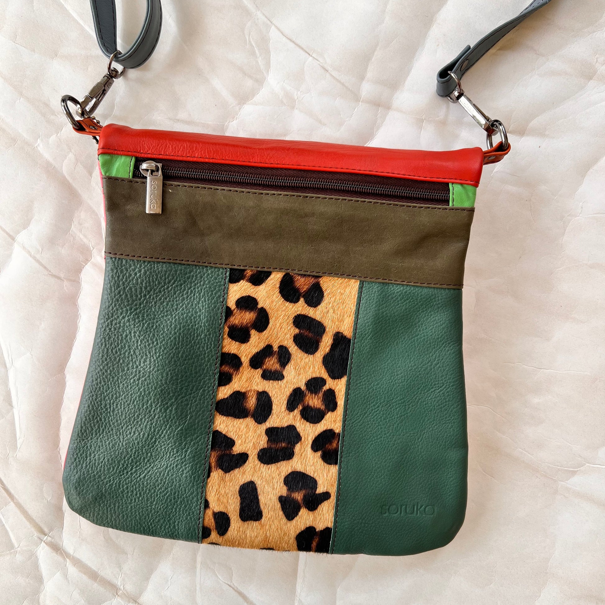 green greta bag with animal print block in the center with olive stripe and zipper across the top.