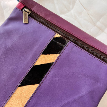 close-up of purple greta bag with animal print stripe down the center and zipper at the top.