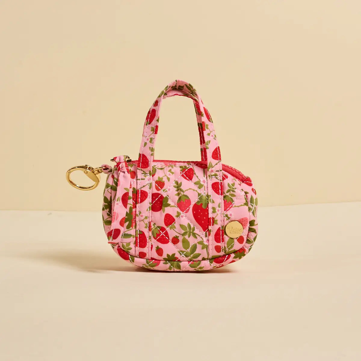 tiny duffle bag with strawberry pattern on a beige background