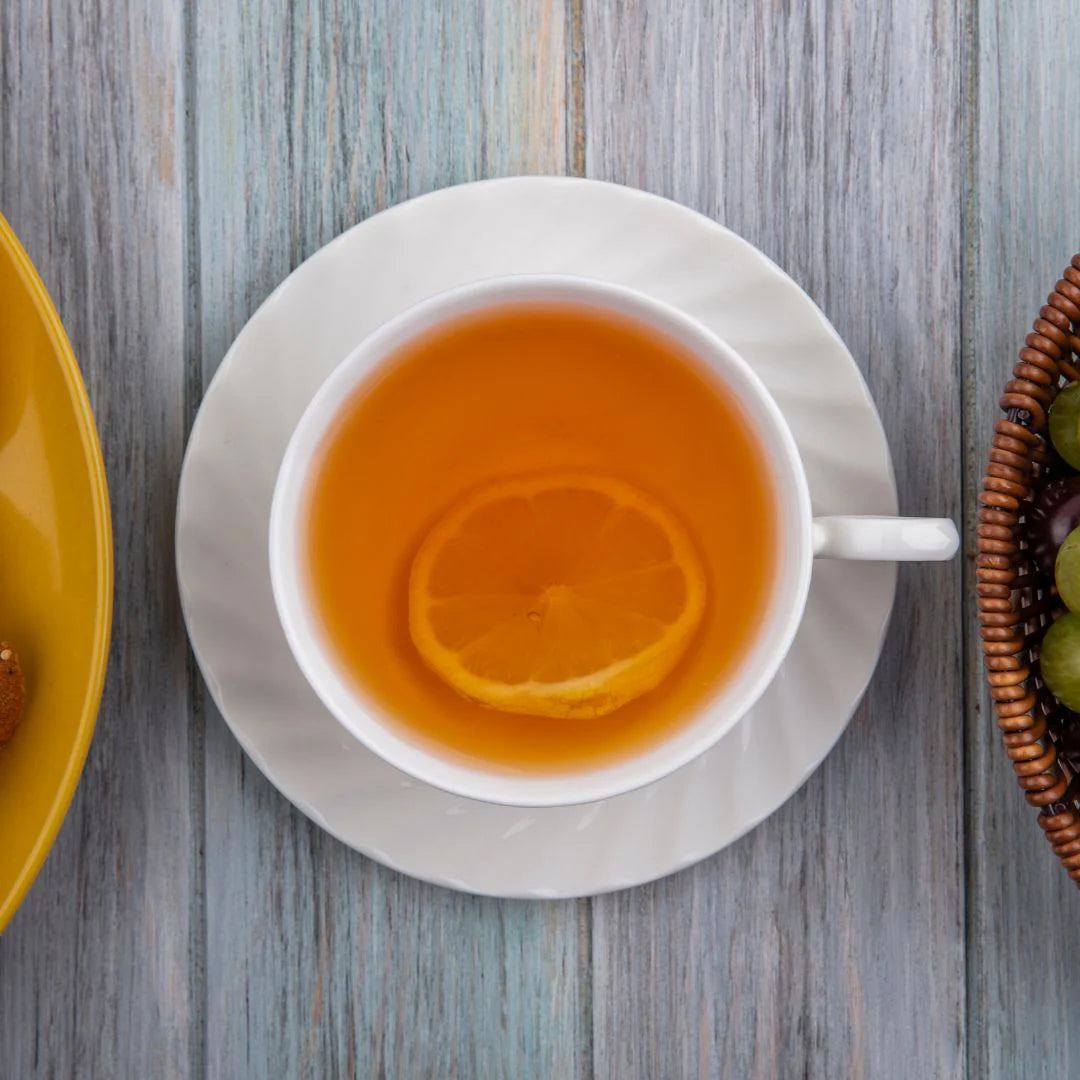 top view of a white cup on a saucer filled with hot toddy and a lemon