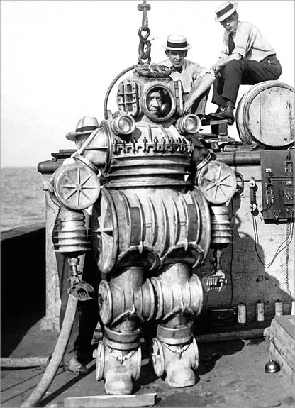 black and white image of person wearing old-fashion metal diving suit with others looking around.