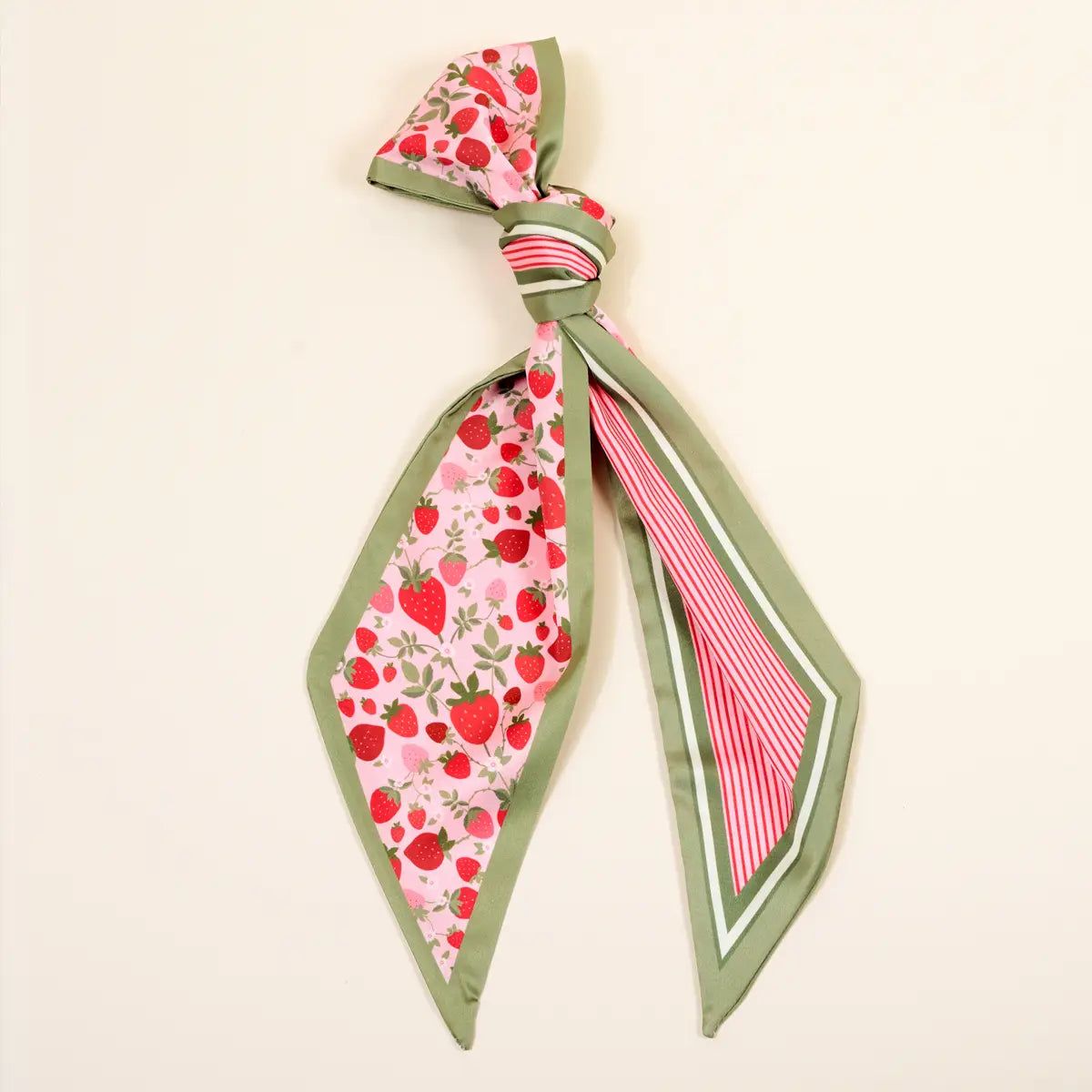 Scarf with strawberry pattern tied in a knot on a beige background