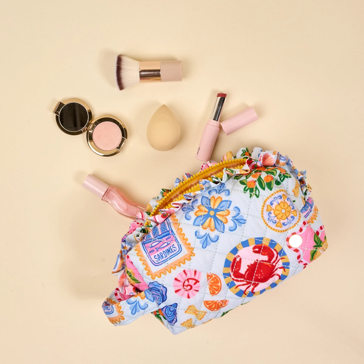Colorful floral-patterned makeup bag with cosmetic items on a beige background