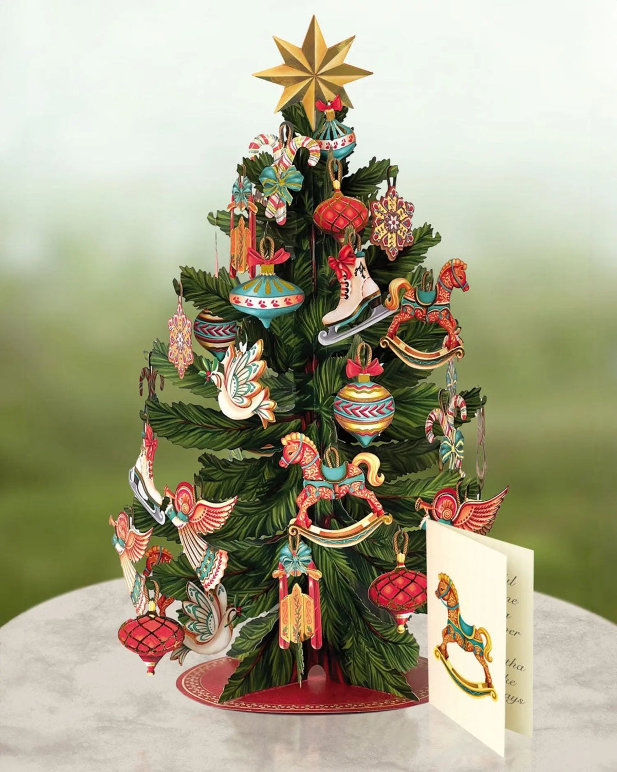 Pop up tree card set on a pedestal with its enclosure card that is printed with a rocking horse design