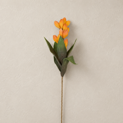 An artificial stem withyellow-orange pods and green leaves shown against a neutral, textured beige wall.