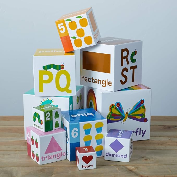 10 blocks of assorted sizes with various colors, number, letters, and images printed on them arranged on a a wooden table.