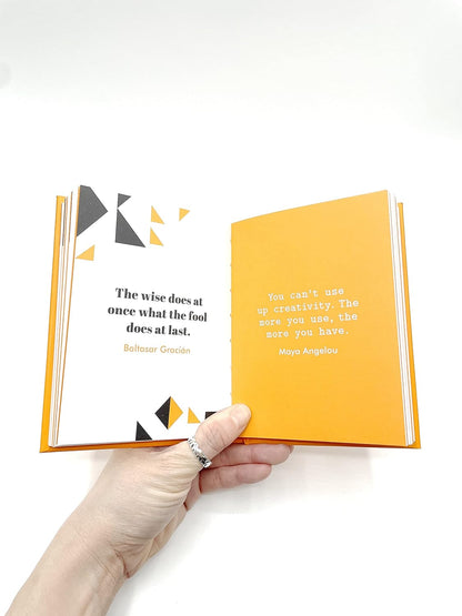 Hand holding an open book with quotes on a white background