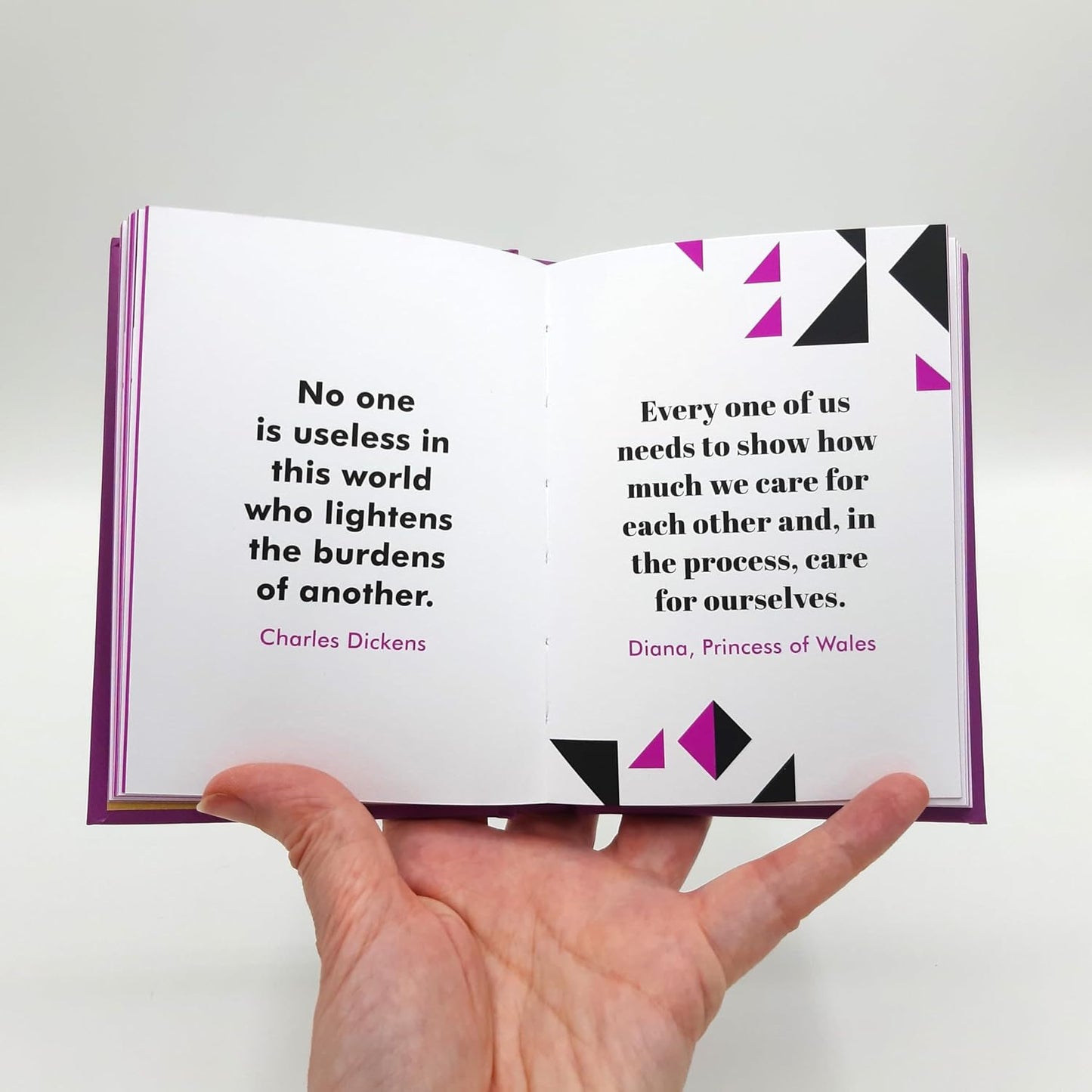 Open book with quotes by Charles Dickens and Princess of Wales held by a hand on a light gray background