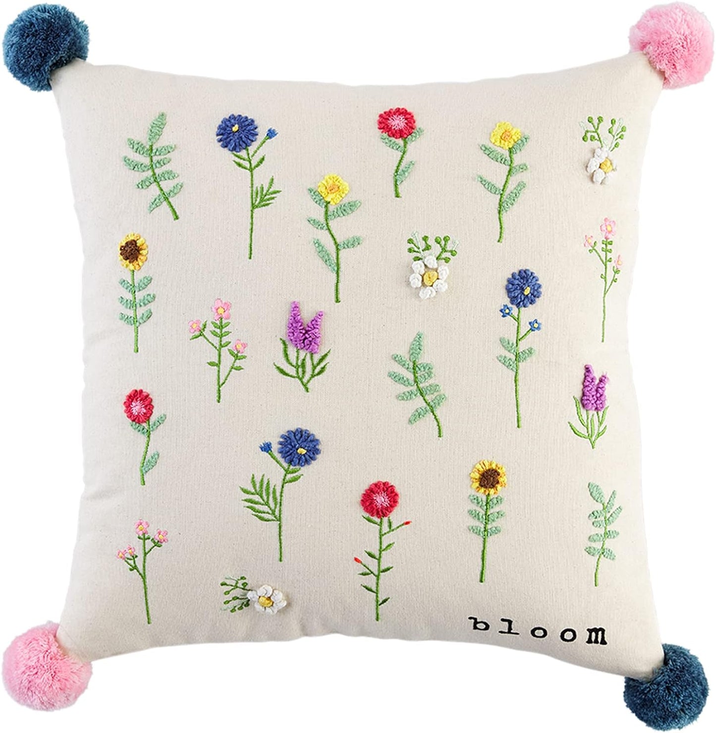 pillow with all-over pattern of embroidered flowers and "bloom" printed in the corner and pink and blue corner poms.