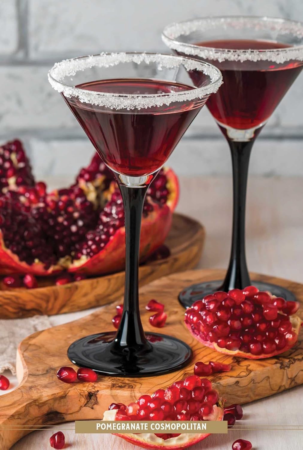 drinks in martini glasses with sugared rims and pomegranates scattered around them