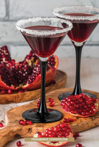 drinks in martini glasses with sugared rims and pomegranates scattered around them