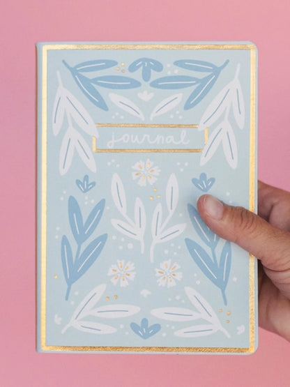 person holding a journal against a pink background
