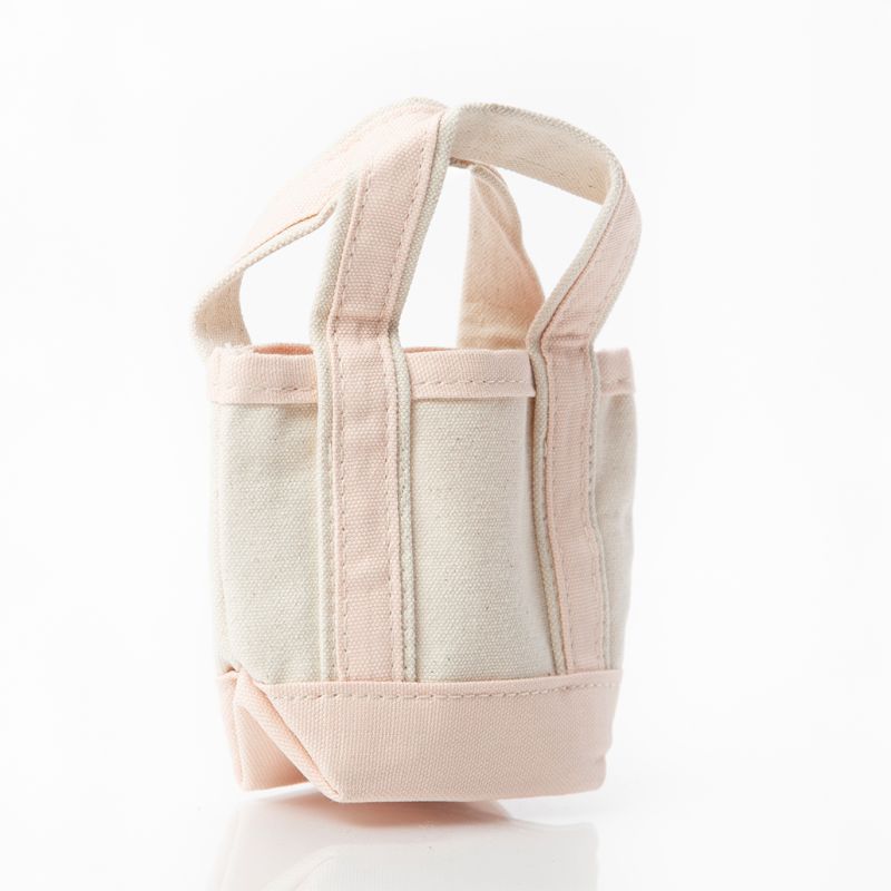 side view of off white mini tote bag with pale pink handles and trim