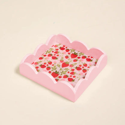 Pink scalloped-edge small tray with strawberry pattern on a beige background