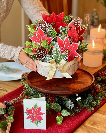 person setting Birch Poinsettia Pop-Up Bouquet on a table