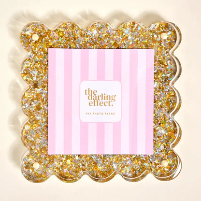 Decorative photo frame with gold glitter and a pink striped insert where photo goes, featuring 'the darling effect' branding.