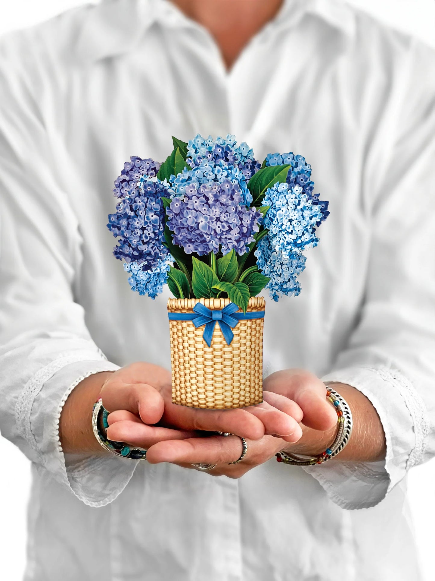 person holding Nantucket Hydrangeas pop-up bouquet in front of them.