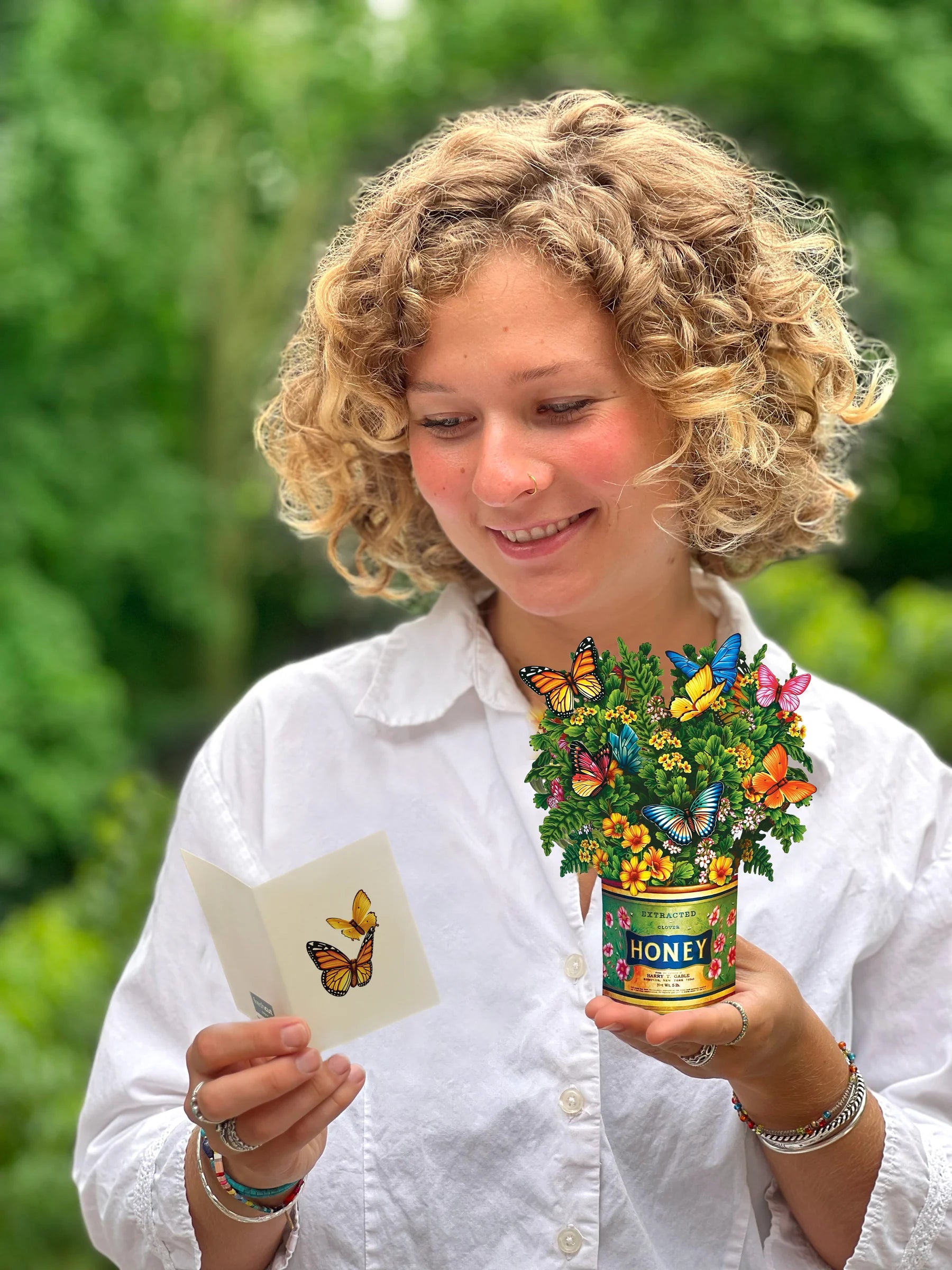 person holding Butterflies & Buttercups pop up bouquet and the enclosure card.