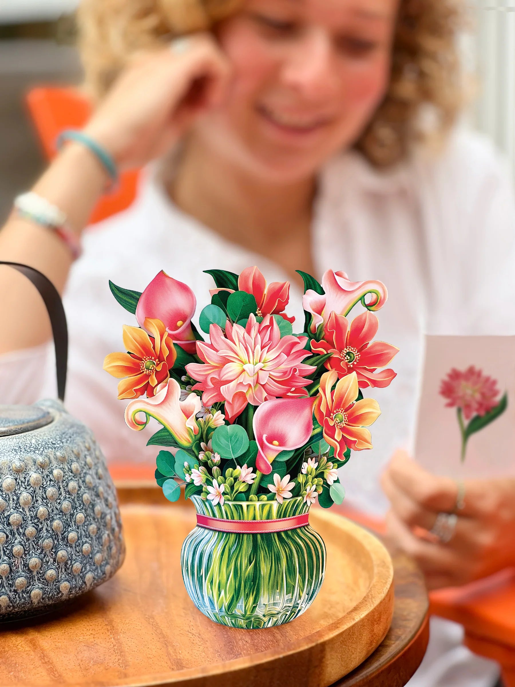 Dear Dahlia pop-up bouquet set on a table with person reading the enclosure card in the background.