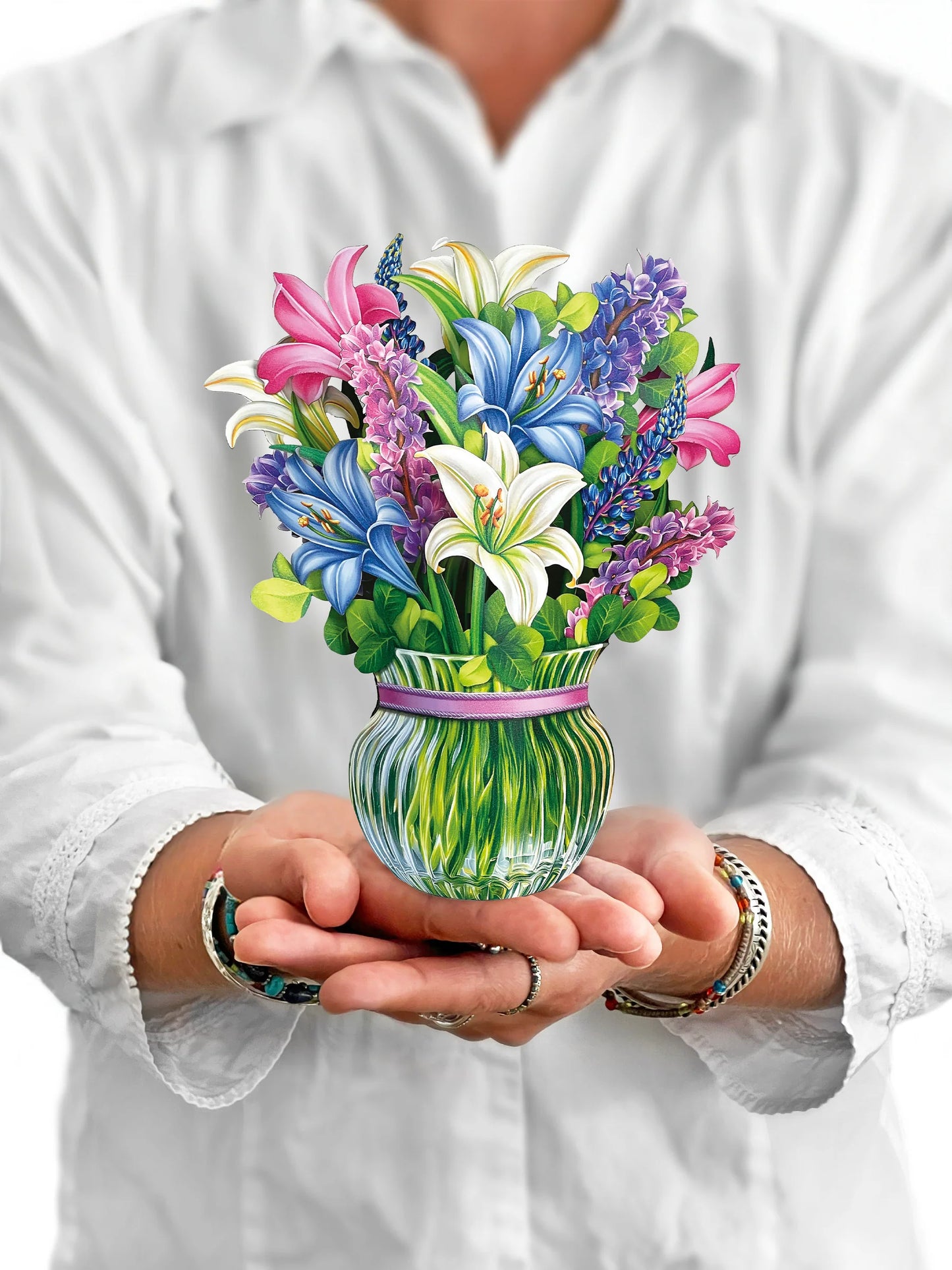 person holding Lilies & Lupines pop-up bouquet in front of them.