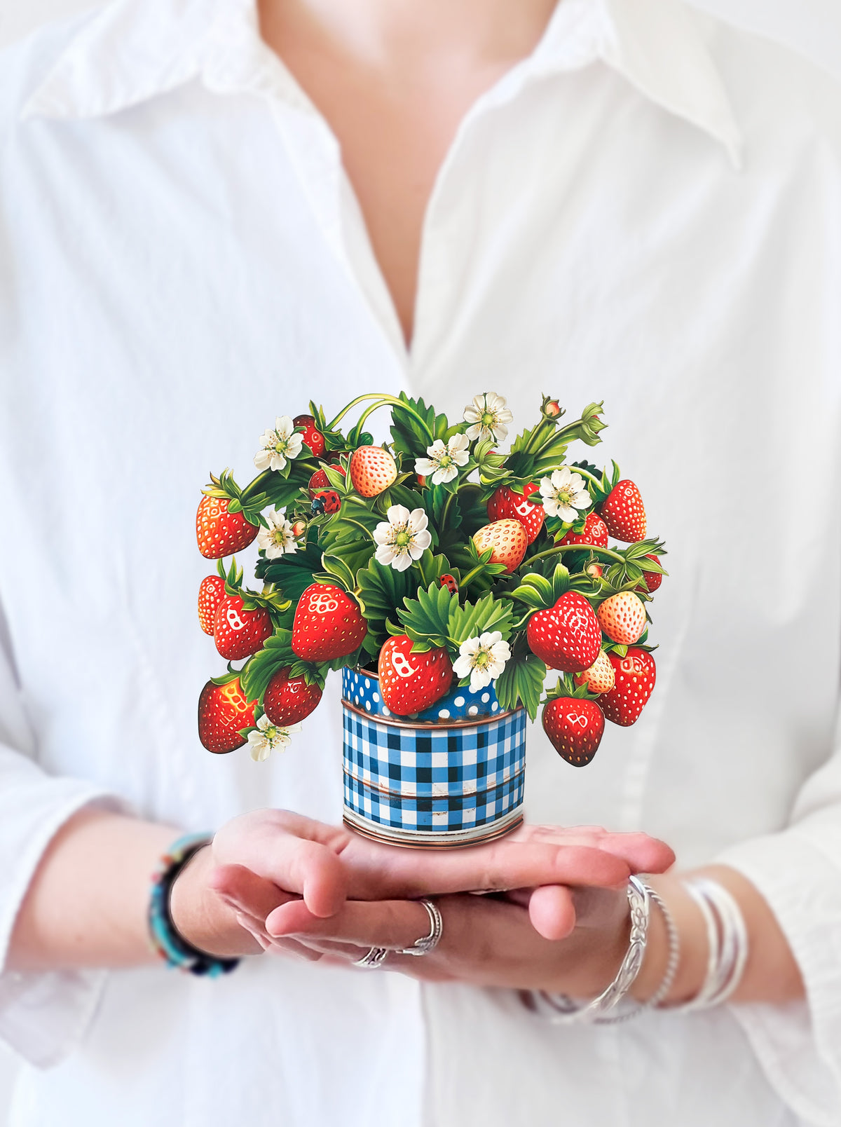 a person holding the mini strawberry blossom bouquet in their hand