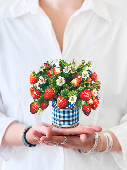 a person holding the mini strawberry blossom bouquet in their hand
