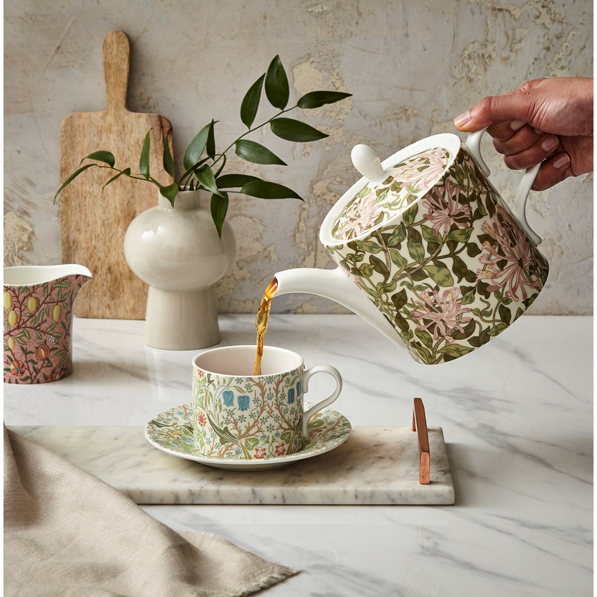 honeysuckle teapot pouring tea into a mug on a decorated table
