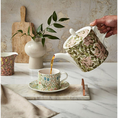 honeysuckle teapot pouring tea into a mug on a decorated table