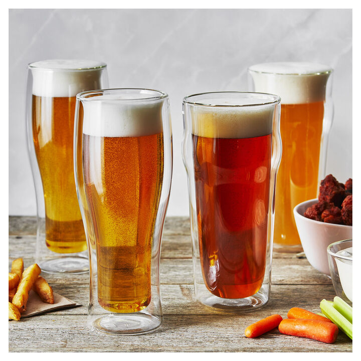 4Double-Wall Beer Glasses filled with beer set on a wooden table with snacks around them.