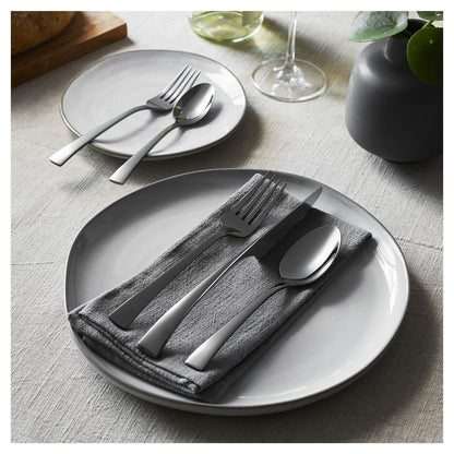 5 piece flatware displayed on a dinner plate and salad plate with a grey napkin.