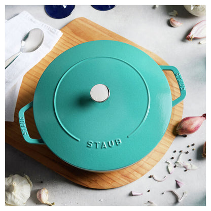 Top view of turquoise French oven set on a wooden board on a kitchen counter