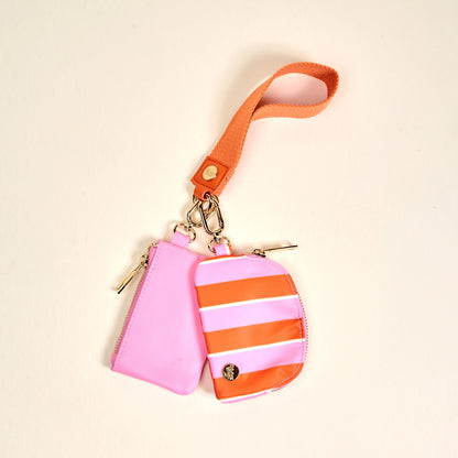 Pink and orange striped keychain pouch with wrist strap on a beige background