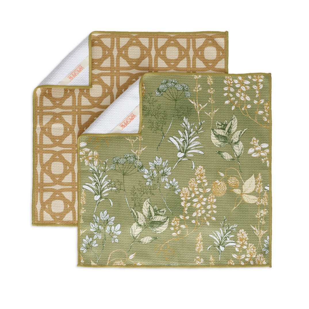 Two different patterns of kitchen herb towels arranged on a white background with corners flapped over, showing hanging loop.