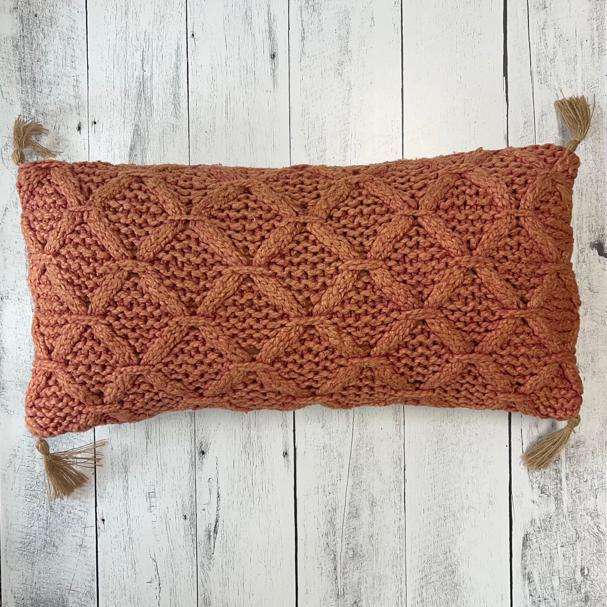 woven dark blush pillow on a white wooden slat background.