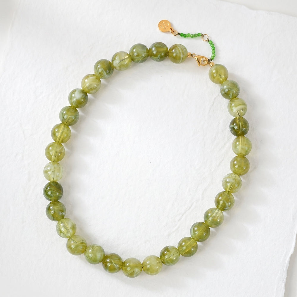 green bead necklace on a textured surface