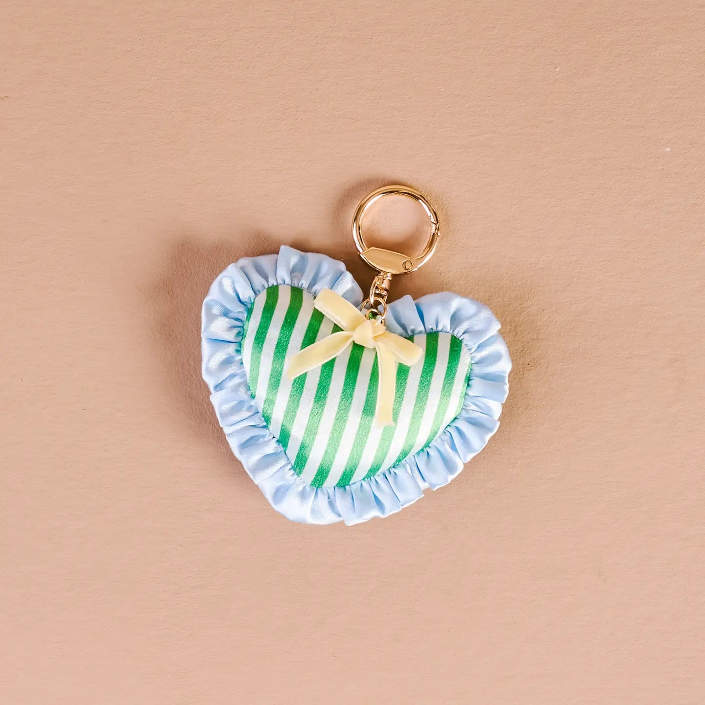 cool crush Heart-shaped bag charm with green and white striped design on a beige background