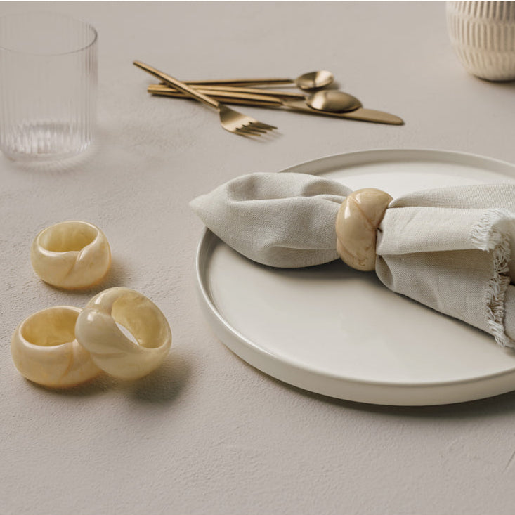 napkin ring on a napkin on a plate with more napkin rings, glasses, and silverware in the background