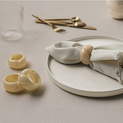 napkin ring on a napkin on a plate with more napkin rings, glasses, and silverware in the background