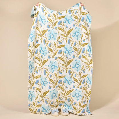 Floral patterned blanket being held up from behind on a beige background