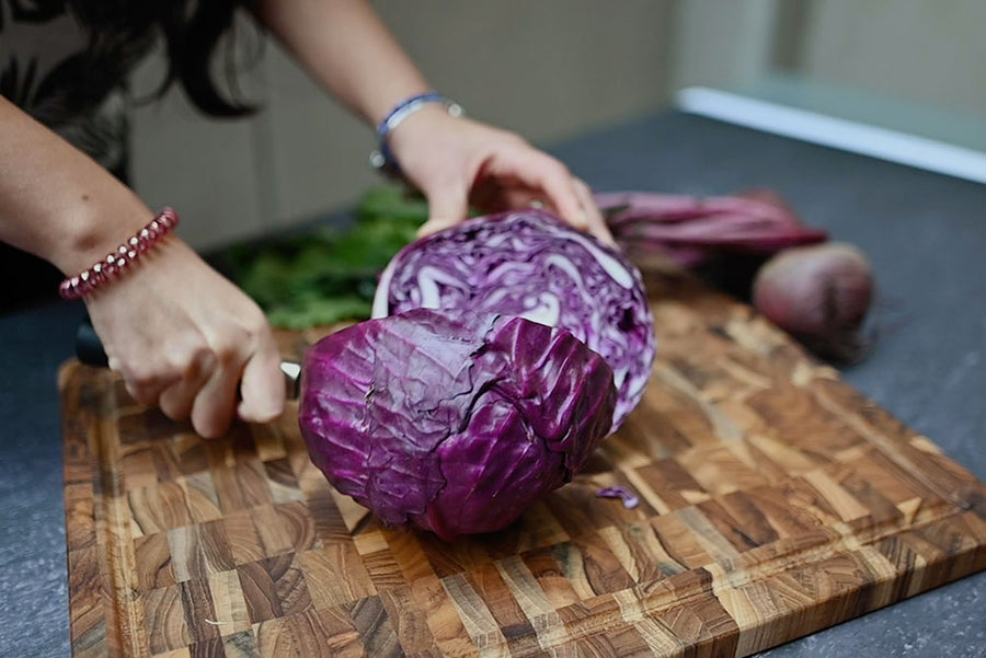 person cutting purple cabbage on an end grain cutting board.