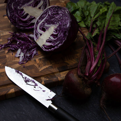 knife and veggies set on an end grain cutting board.