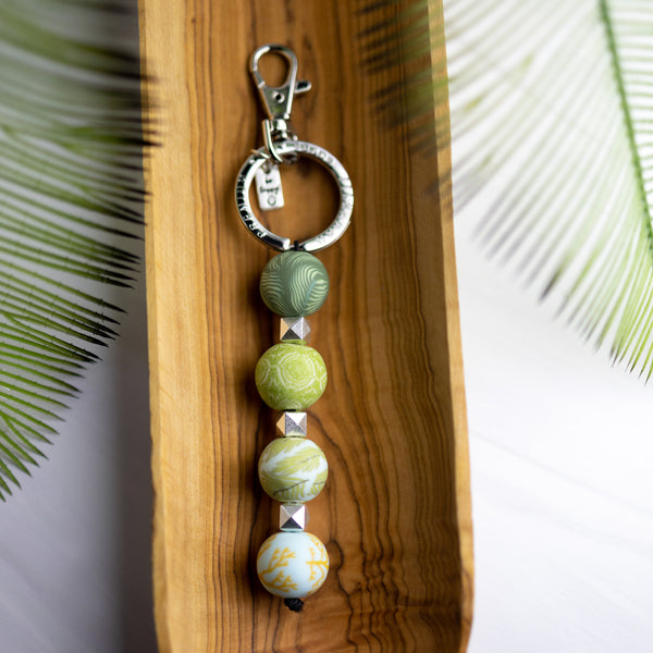 keychain with 4 green and teal patterned beads, silver spacer beads and silver keyring.