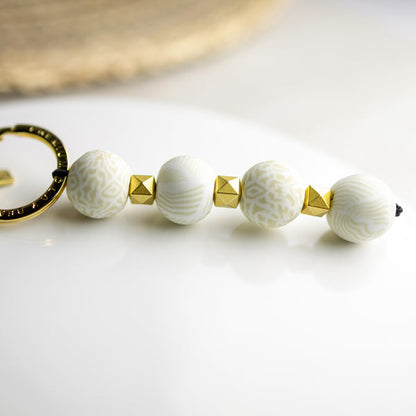 keychain with 4 ivory and taupe patterned beads, gold spacers and gold keyring.