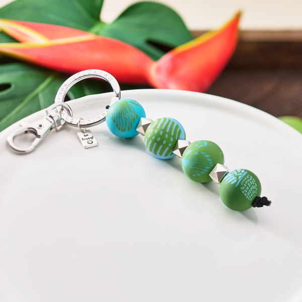 Tropical Green Four-Ball Keychain laying on a dish with leaves in the background