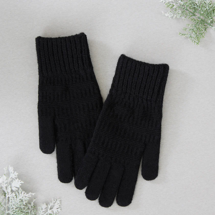 Black gloves arranged on a light Grey surface with greenery