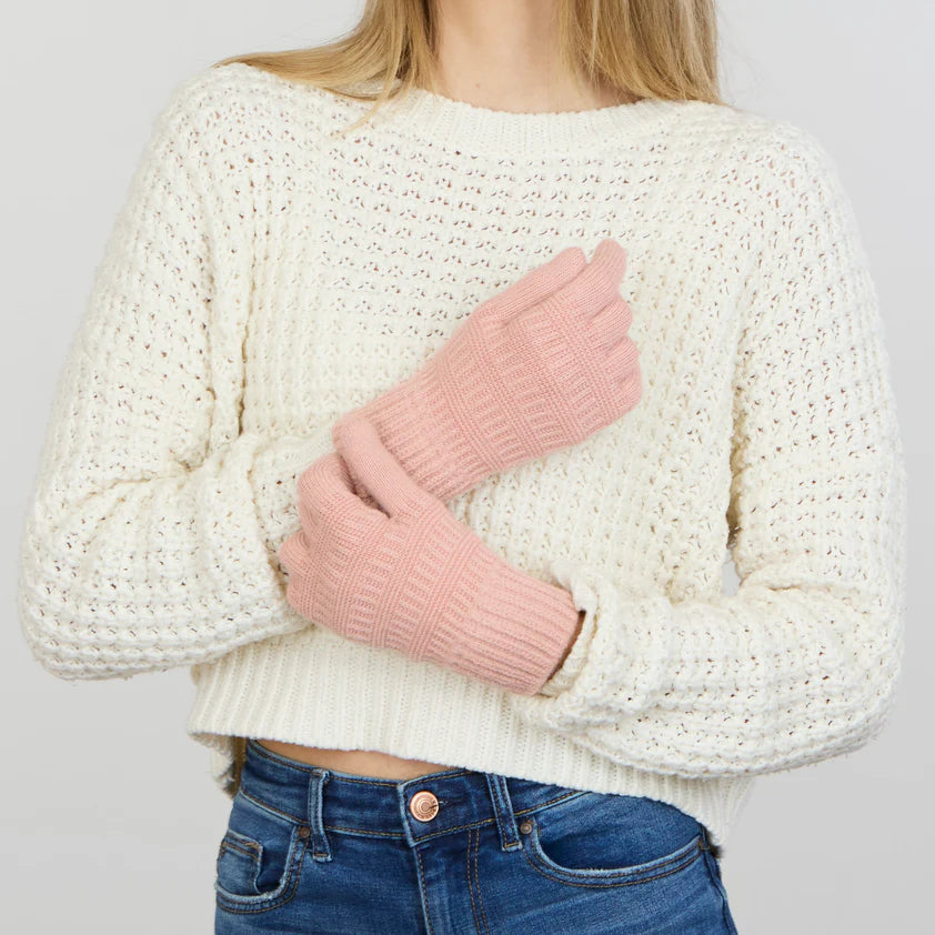 person wearing jeans, a white sweater, and pink gloves