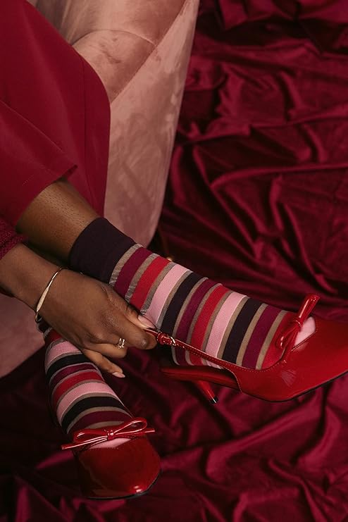 Person wearing red shoes and striped socks on a red fabric background
