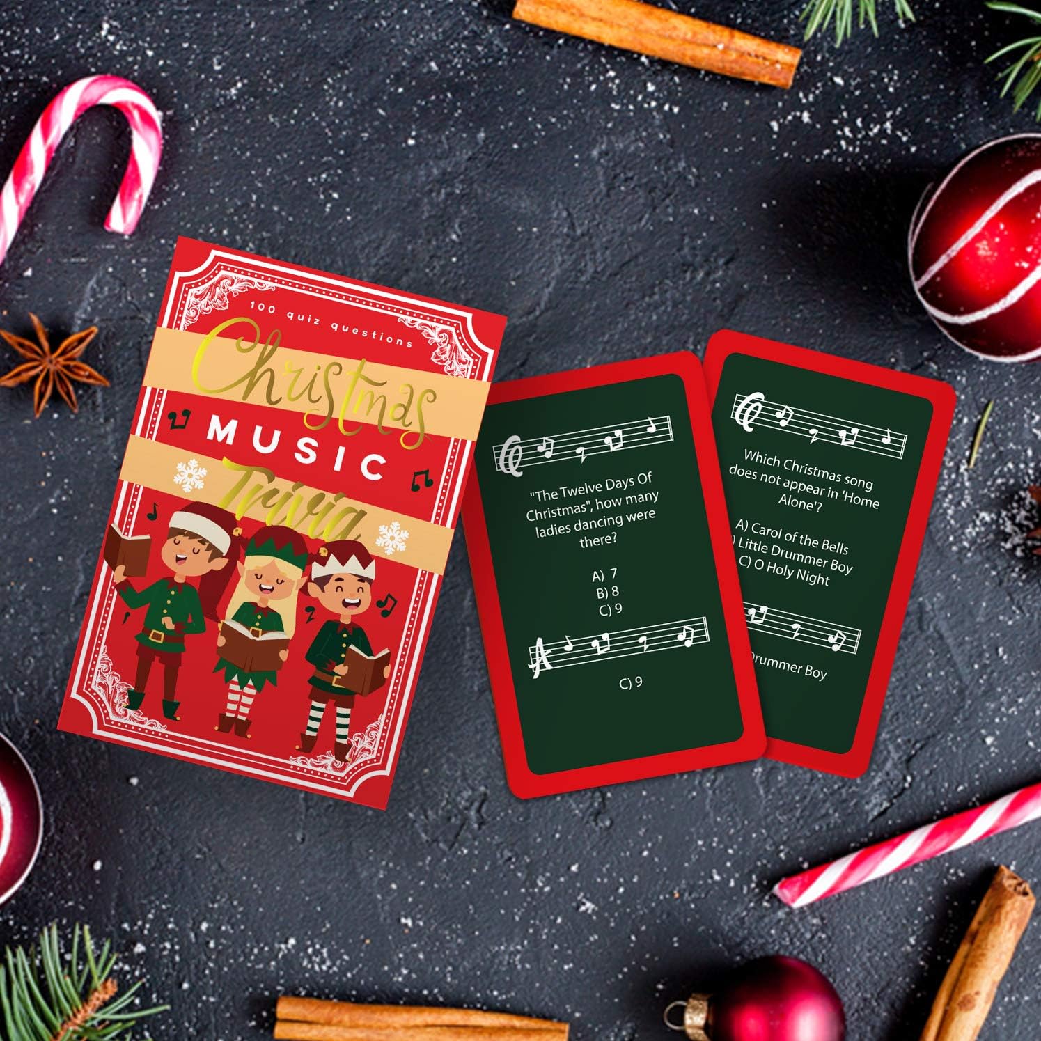 Christmas Music Trivia box and cards arranged on a black stone counter with candy canes and spices.