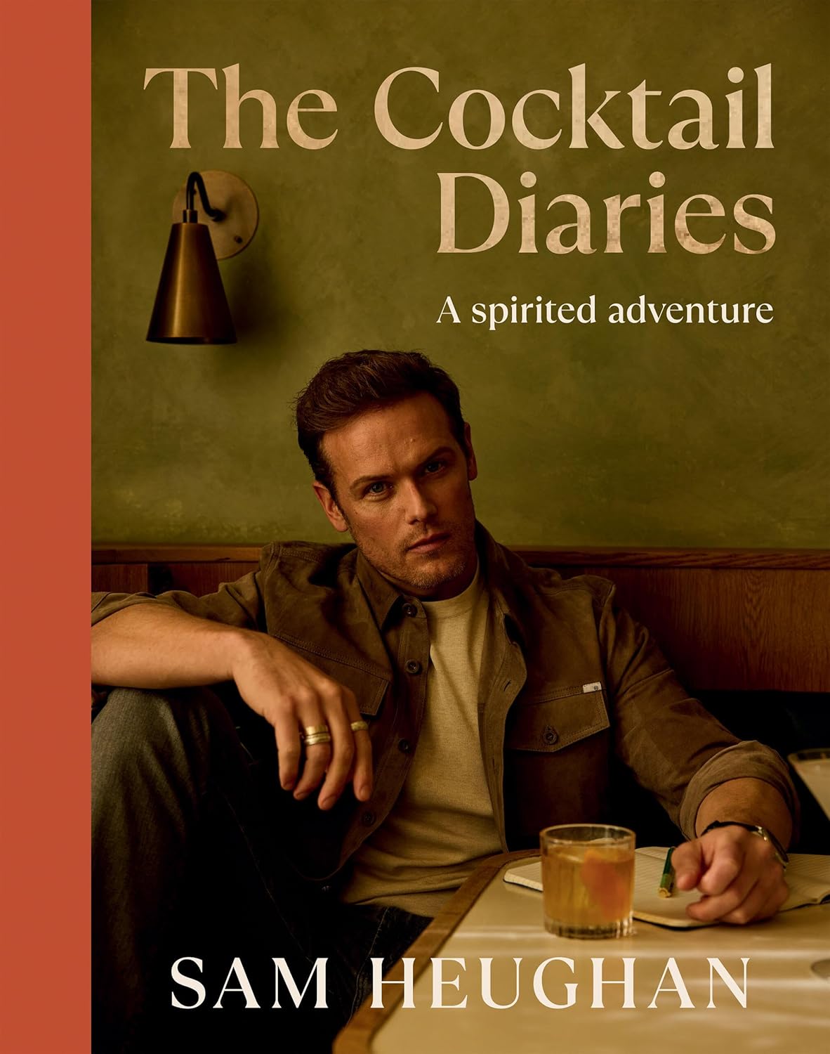 book cover of a person sitting at a table with a journal and cocktail with tan title text